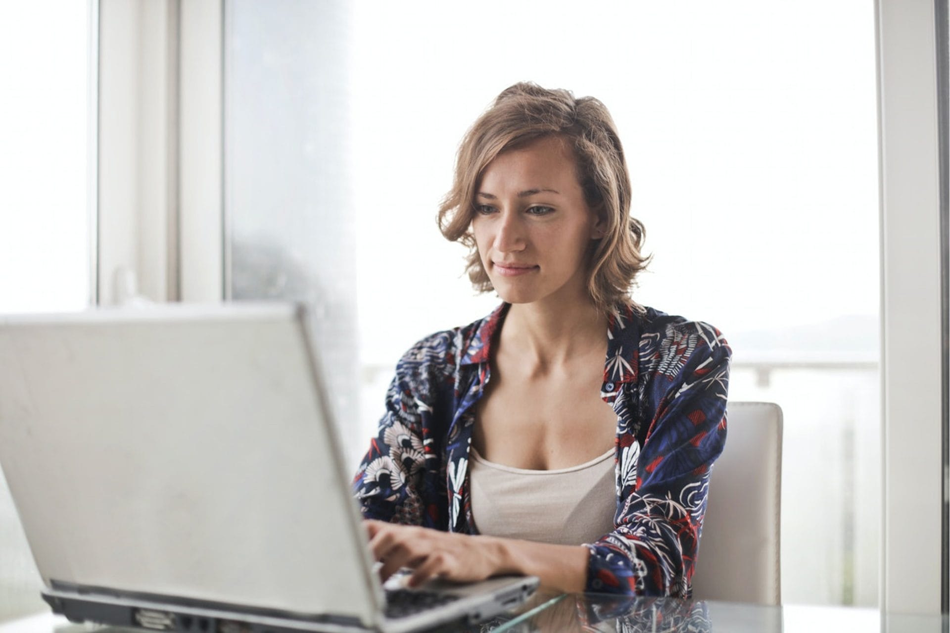 Woman browsing her laptop, smiling