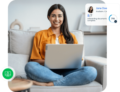 Smiling woman sitting on a couch using a laptop to complete onboarding documents in a client portal.